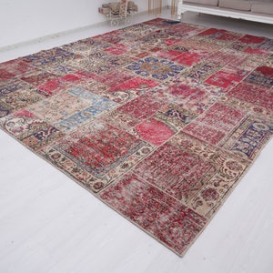 K&ouml;nnte beinhalten: Ein mehrfarbiger Patchwork-Teppich mit verschiedenen floralen und geometrischen Mustern. Der Teppich ist aus einem weichen, gewebten Material gefertigt und hat einen abgenutzten, Vintage-Look.