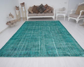 May include: A teal blue vintage rug with a distressed look. The rug has a subtle pattern and is perfect for adding a touch of bohemian style to any room.