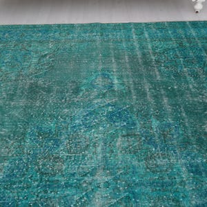 May include: A teal blue vintage rug with a faded pattern. The rug has a distressed look and is made of a soft, woven material.
