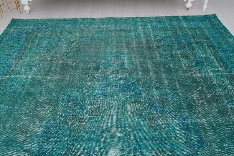 May include: A teal blue vintage rug with a faded pattern. The rug has a distressed look and is made of a soft, woven material.