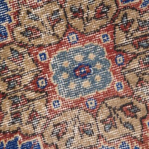 K&ouml;nnte beinhalten: Nahaufnahme eines Vintage-Teppichs mit einem detaillierten Muster in Rot-, Blau- und Beiget&ouml;nen. Der Teppich hat ein zentrales Medaillon mit komplizierten floralen Designs.