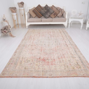 May include: A rectangular area rug featuring a faded, distressed pattern in shades of soft pink, cream, and muted grey. The design includes a central medallion surrounded by intricate floral and geometric motifs with a fringed edge finish.