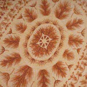 Puede incluir: Una alfombra beige y marr&oacute;n con un patr&oacute;n circular de hojas y flores. La alfombra tiene un dise&ntilde;o detallado y una est&eacute;tica vintage.