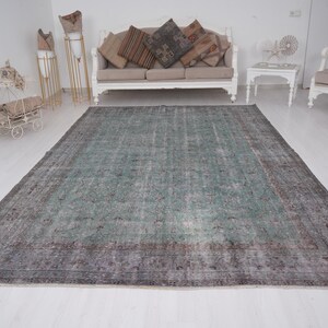 May include: A vintage teal and gray area rug with a faded floral pattern. The rug has a distressed look and is perfect for adding a touch of bohemian style to any room.