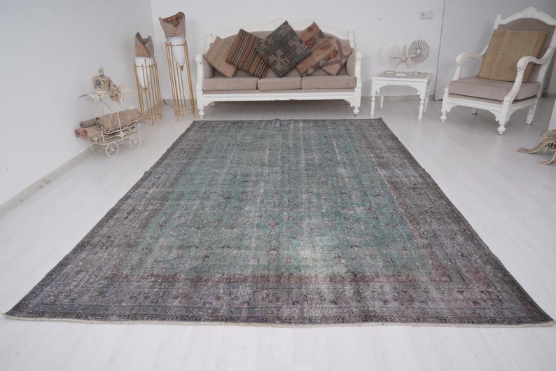 May include: A vintage teal and gray area rug with a faded floral pattern. The rug has a distressed look and is perfect for adding a touch of bohemian style to any room.
