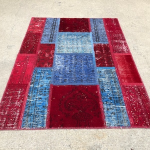 May include: A patchwork rug featuring a combination of red and blue colours. The rug is constructed from various pieces of fabric stitched together. The rug has a distressed appearance, with some of the fabric exhibiting signs of wear and tear.