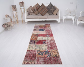 May include: A colorful patchwork runner rug with a red, blue, and cream color scheme. The rug is made of recycled materials and has a distressed look.