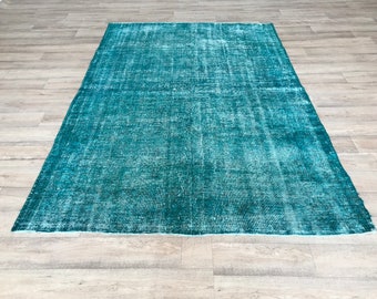 May include: A teal blue vintage rug with a distressed look. The rug has a faded, worn appearance, giving it a unique and rustic charm.