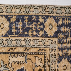 May include: A vintage rug with a blue and beige pattern. The rug has a fringe border and intricate floral designs.