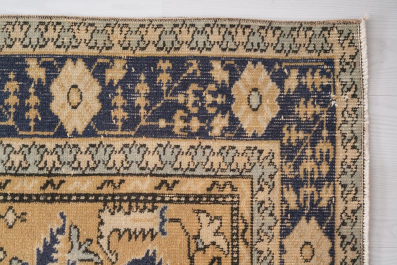 May include: A vintage rug with a blue and beige pattern. The rug has a fringe border and intricate floral designs.