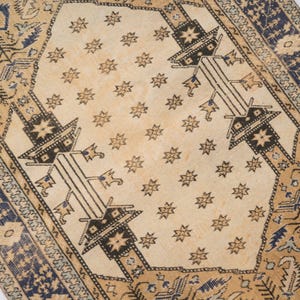 May include: A vintage rug with a cream background and a repeating pattern of stars and geometric shapes in black and blue. The rug has a border with a floral design.