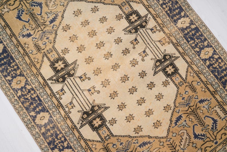 May include: A vintage rug with a cream background and a repeating pattern of stars and geometric shapes in black and blue. The rug has a border with a floral design.