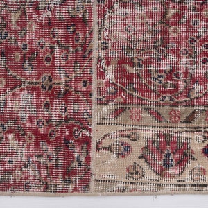K&ouml;nnte beinhalten: Ein Vintage-Teppich in Rot und Beige mit einem floralen Muster. Der Teppich hat einen abgenutzten und verblassten Look, der ihm ein rustikales und antikes Aussehen verleiht.