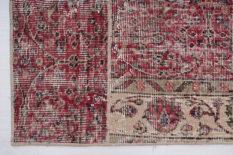 K&ouml;nnte beinhalten: Ein Vintage-Teppich in Rot und Beige mit einem floralen Muster. Der Teppich hat einen abgenutzten und verblassten Look, der ihm ein rustikales und antikes Aussehen verleiht.
