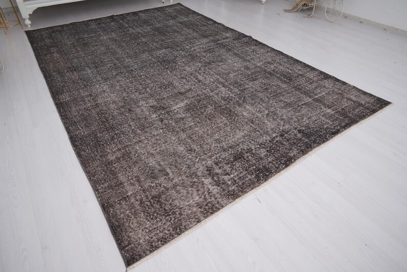 May include: A dark gray vintage rug with a faded, distressed look. The rug has a subtle pattern and a soft, worn texture.