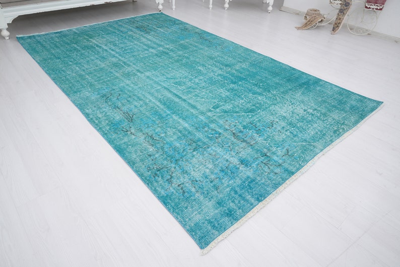 May include: A turquoise blue vintage rug with a faded pattern. The rug has a white fringe border.