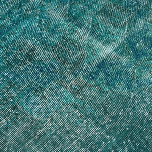 May include: A teal blue rug with a faded, distressed pattern. The rug has a textured, woven surface.