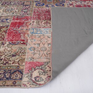 K&ouml;nnte beinhalten: Ein Patchwork-Teppich mit verschiedenen Farben und Mustern, darunter Rot, Blau und Beige. Der Teppich hat eine graue R&uuml;ckseite und ist in der Mitte gefaltet.