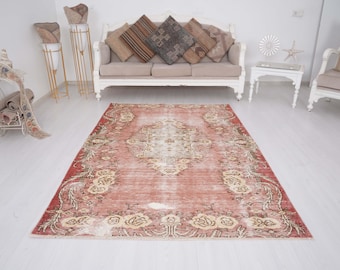 Op de afbeelding: Een rechthoekig vloerkleed met een vervaagde terracotta rode basis, een centraal crèmekleurig medaillon en ingewikkelde florale randpatronen in beige en witte tinten, met een versleten textuur over het gehele oppervlak.