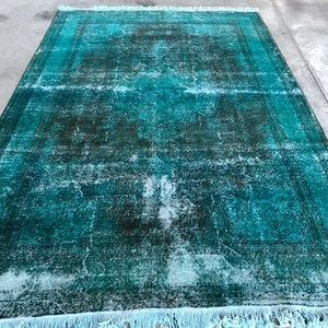 Può includere: Un tappeto vintage blu turchese con un aspetto sbiadito e usurato. Il tappeto ha una frangia blu chiaro attorno ai bordi.