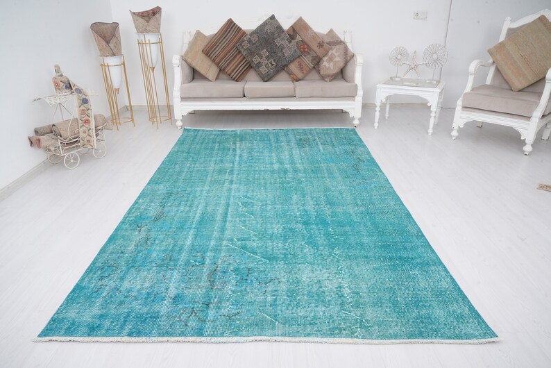 May include: A teal blue vintage rug with a distressed look. The rug has a faded, worn appearance, giving it a unique character.