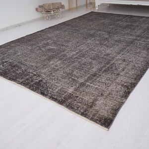 May include: A dark gray vintage rug with a distressed, faded look. The rug has a subtle pattern and a slightly textured surface.