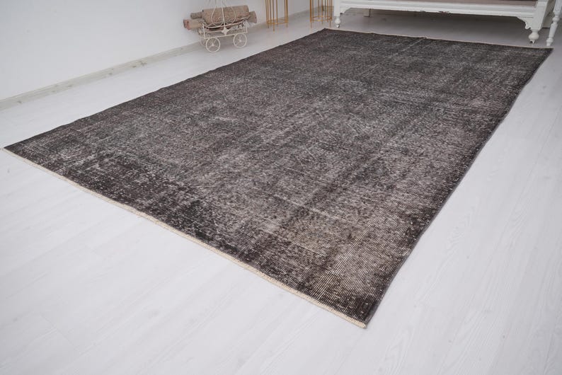 May include: A dark gray vintage rug with a distressed, faded look. The rug has a subtle pattern and a slightly textured surface.