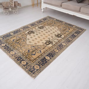 May include: A vintage rug with a cream background and a navy blue border. The rug has a traditional Persian design with intricate floral patterns.