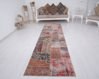 May include: A colorful patchwork runner rug with a distressed look. The rug is made up of various shades of red, blue, and beige. It is perfect for adding a touch of bohemian style to any room.
