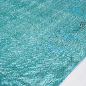 May include: A teal blue rug with a distressed, vintage look. The rug has a subtle pattern and a soft, faded texture.
