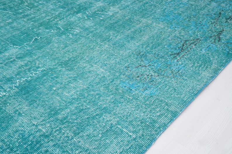 May include: A teal blue rug with a distressed, vintage look. The rug has a subtle pattern and a soft, faded texture.