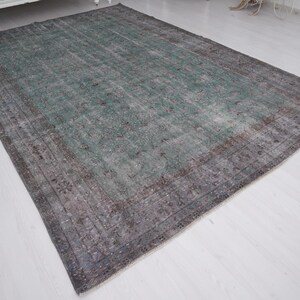 May include: A vintage rug with a faded green and gray color scheme. The rug has a distressed look with a subtle pattern.