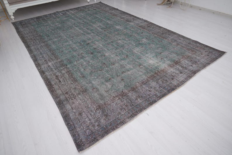May include: A vintage rug with a faded green and gray color scheme. The rug has a distressed look with a subtle pattern.