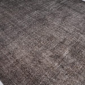 May include: A close-up of a dark gray rug with a subtle pattern. The rug has a distressed, vintage look and is made of a soft, woven material.