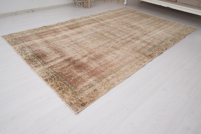 May include: A rectangular, distressed-look rug with a faded, vintage appearance. The rug features a central field of beige and brown tones, with a darker border. The design includes floral and geometric patterns.