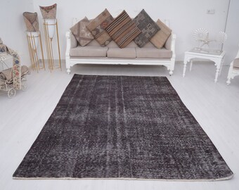 Puede incluir: Una alfombra vintage gris oscuro con un aspecto desgastado. La alfombra tiene un patrón sutil y es perfecta para agregar un toque de encanto rústico a cualquier habitación.