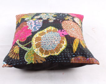May include: A black cotton cushion cover with a floral pattern in shades of pink, blue, green, and brown. The cushion cover is quilted and has a decorative stitch around the edges.