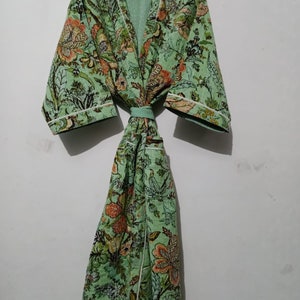 May include: A green floral print robe with a white trim and a matching sash. The robe has a long, flowing silhouette and a relaxed fit.