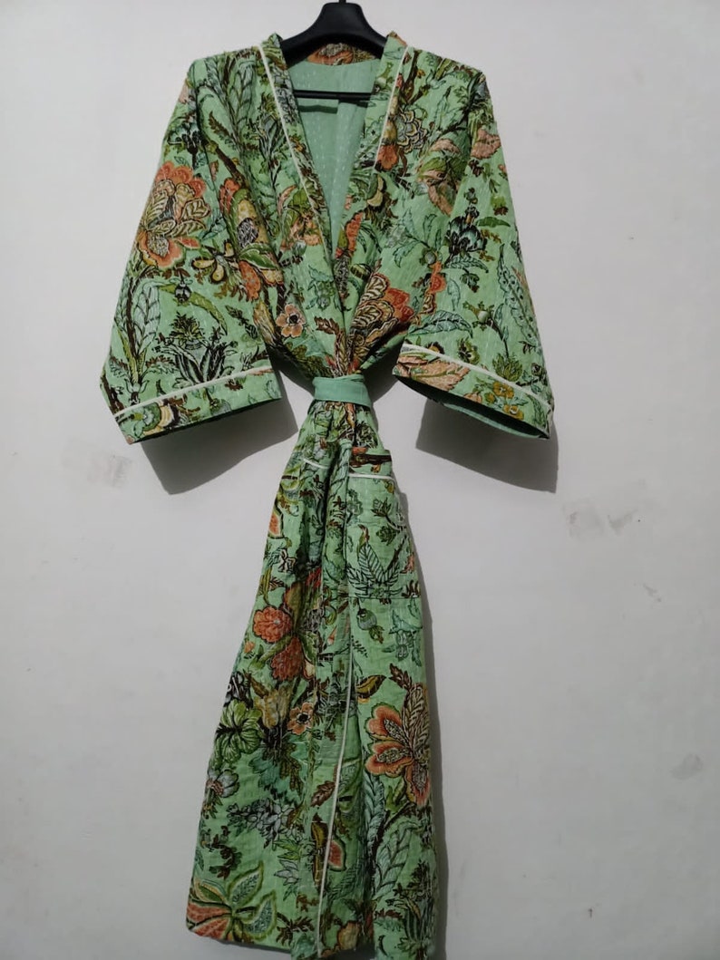 May include: A green floral print robe with a white trim and a matching sash. The robe has a long, flowing silhouette and a relaxed fit.