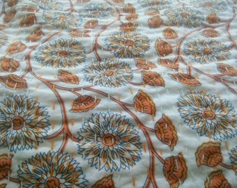Könnte beinhalten: Weißer Stoff mit einem sich wiederholenden Muster aus orangefarbenen und blauen Blumen. Der Stoff hat eine subtile Textur und ein leicht zerknittertes Aussehen.