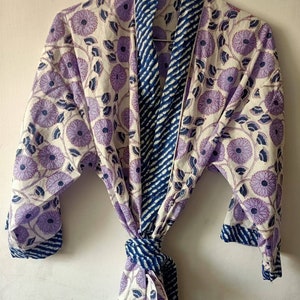 May include: A white cotton robe with a purple floral print and blue striped trim. The robe has a tie belt and long sleeves.
