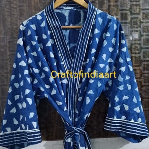 May include: A blue cotton robe with a white geometric pattern and white trim. The robe has a tie belt and long sleeves.