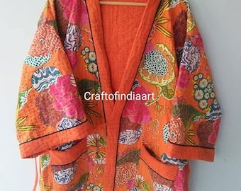 Puede incluir: Bata de algodón naranja con estampado floral y ribete negro. La bata tiene una abertura delantera larga y un cinturón de atar. La tela es suave y cómoda.