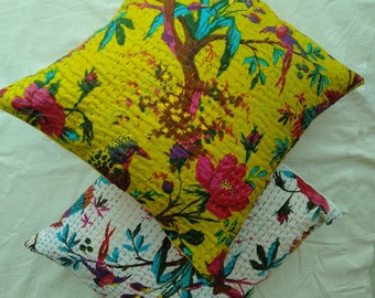 May include: Two decorative throw pillows with floral patterns. The top pillow is yellow with a floral and bird design. The bottom pillow is white with a floral and bird design.