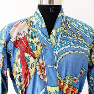 Puede incluir: Una bata de algod&oacute;n azul con ribete blanco y estampado floral y de p&aacute;jaros de colores. La bata tiene un cuello de estilo japon&eacute;s tradicional.