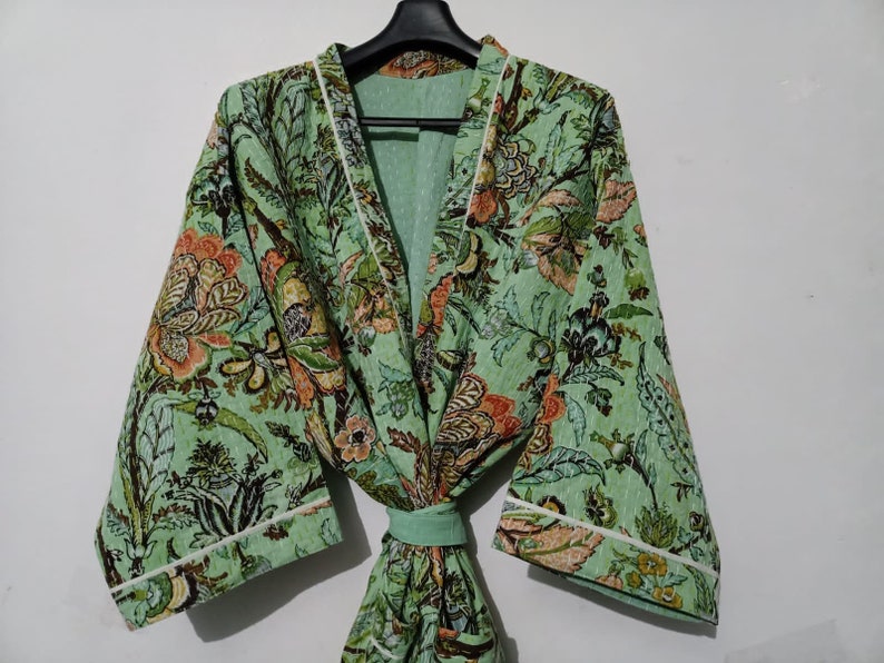 May include: A green floral print robe with white trim. The robe has a long sleeve and a tie belt.