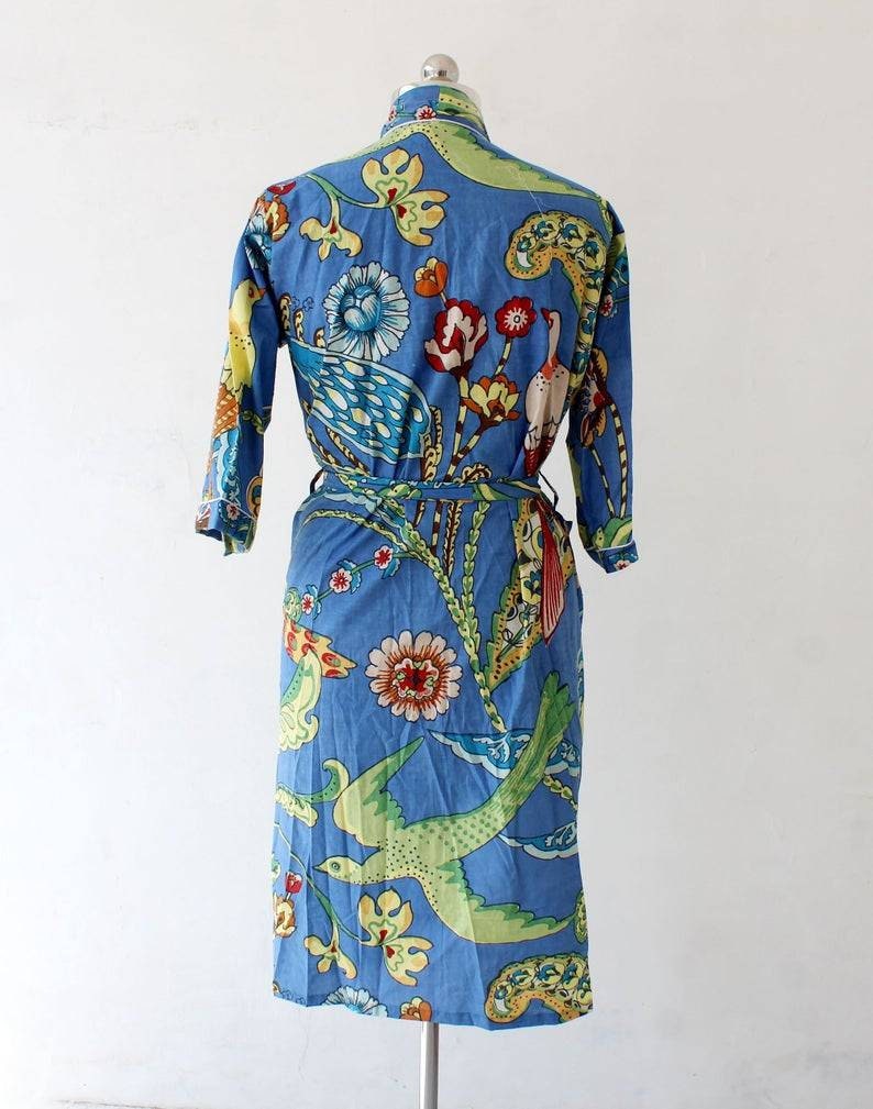 Puede incluir: Una bata de algod&oacute;n azul con estampado floral y de p&aacute;jaros. La bata tiene un cintur&oacute;n de atar y mangas largas.