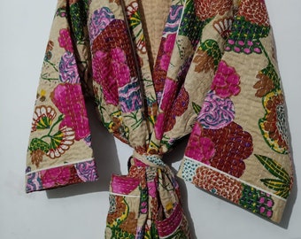 Puede incluir: Una bata acolchada beige con estampado floral en tonos rosa, verde y marrón. La bata tiene un cinturón de atar y mangas largas.