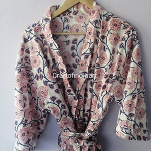 May include: A white cotton robe with a pink and blue floral print. The robe has a shawl collar, a tie belt, and three-quarter sleeves.