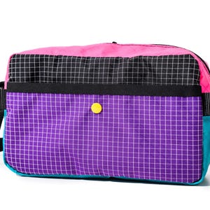 May include: A colorful crossbody bag with a vibrant design. The bag features a pink top, a black and white checkered middle section, and a purple grid-patterned bottom. It has a teal side, a yellow button, and a black strap.